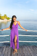 © Oren Thomas - Beautiful black woman wearing a long purple dress smiles while standing on a pier in the morning sunshine
