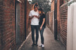 © Cavan Images - Couple smiling and looking the phone together on the street in summer