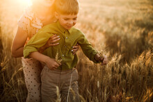 A Mother And Son Playing Together In The Wheat Fields During Sunset