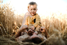 A Mother And A Son Playing Together In The Wheat Fields During Sunset