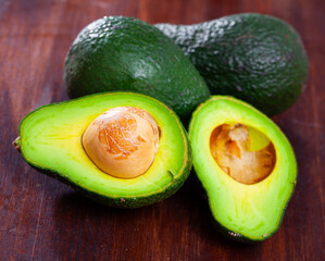 Wall Mural - Image of close up of cut avocado with bone at wooden table