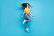 Full length photo of sweet shiny girl dressed yellow t-shirt smiling jumping high isolated blue color background