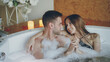 © silverkblack - Loving young people in bathing suits are talking, hugging and touching hands in hot bathtub in spa salon. Romantic relationship, passion and wellness concept.