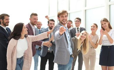 happy business man standing among colleagues and pointing at you.