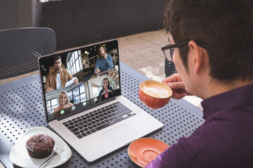 Sticker - Over shoulder view of asian man drinking coffee having laptop video call with diverse colleagues