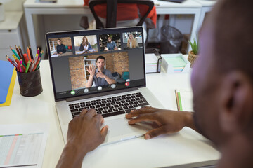 Poster - Over shoulder view of african american businessman making laptop video call with diverse colleagues
