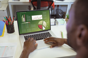 Wall Mural - Over shoulder view of african american businessman using laptop with data processing on screen