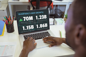 Poster - Over shoulder view of african american businessman using laptop with user growth figures on screen