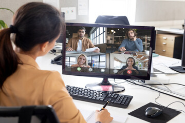 Poster - Over shoulder view of asian businesswoman making video call with diverse colleagues on screen