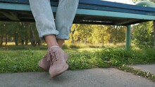 Girl Dangling Her Feet In Jeans And Pink Shoes. Woman Swinging Legs In Boredom, Sitting At Park On A Bench.