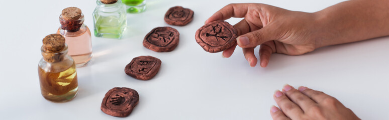 Wall Mural - cropped view of predictor holding clay rune near bottles with essential oils, banner.