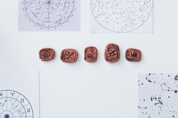 Wall Mural - top view of celestial charts and clay runes on white table.