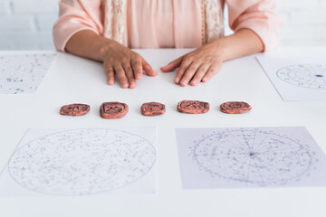 Wall Mural - partial view of astrologist near clay runes and cosmic maps.