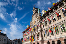 City Hall Antwerp Belgium With Blue Sky With Colorful Flags. Renaissance Building With Flemish And Italian Influences Is A Major Sight And World Heritage Monument At The “Grote Markt“ In Town Centre. 