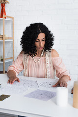 Wall Mural - brunette astrologist near natal charts and candles on table.