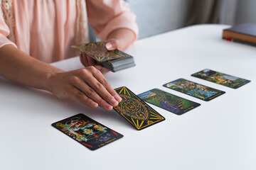 Wall Mural - KYIV, UKRAINE - JUNE 29, 2022: partial view of fortune teller laying out tarot cards on table.