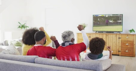 Wall Mural - Video of african american family sitting on sofa and watching football at home