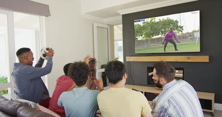 Wall Mural - Video of diverse friends sitting on sofa and watching football on television at home