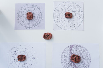 Wall Mural - top view of clay runes and constellation charts on white surface.