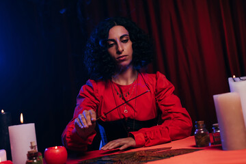Wall Mural - young fortune teller holding palo santo stick near tarot cards on dark background.