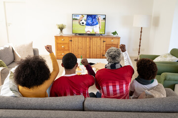 Wall Mural - Happy african american family watching football match together and sitting on the couch