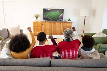 Wall Mural - Happy african american family watching football match together and sitting on the couch