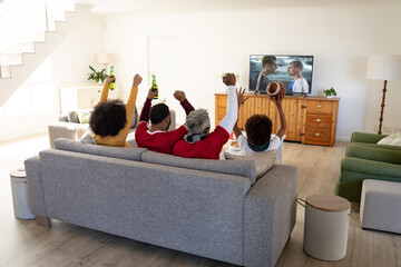 Wall Mural - Happy african american family watching football match together and sitting on the couch