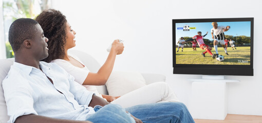 Wall Mural - Happy african american couple watching football match together and sitting on the couch