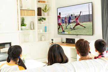 Wall Mural - Diverse group of children watching football match siting together on the couch