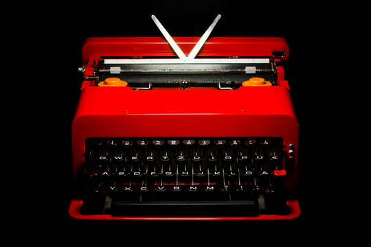 A vintage red typewriter from the 60s valentine portable in perfect mint condition design classic icon italian on black background Mid Century retro furniture office equipment writer  HIGH RESOLUTION