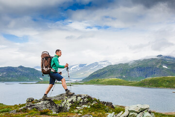 Hiker with backpack walking in Norway mountains. Fitness and healthy lifestyle