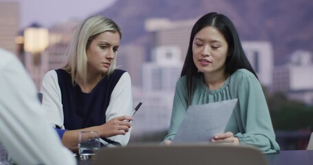 Wall Mural - video of two diverse female colleagues discussing document at evening office meeting