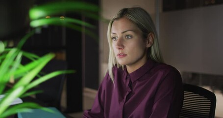 Wall Mural - Video of caucasian businesswoman using computer, working at night in office