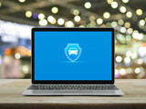 Fototapeta Panele - Car with shield flat icon on modern laptop computer monitor screen on wooden table over blur light and shadow of shopping mall, Business automobile insurance online concept
