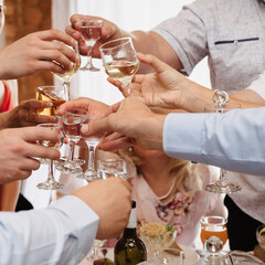 group of friends clink glasses with wine and celebrate the holiday at a festive table