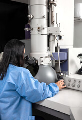 Wall Mural - Young female scientist working at the laboratory with an electron microscope