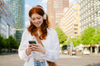 © Drobot Dean - Young beautiful smiling redhead girl in headphones holding her phone