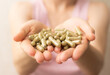 handful of green kratom pills in woman hands, no face, selective focus