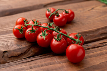 Wall Mural - Cherry tomatoes on a wooden background. Fresh tomato branch. Vegetarian food.