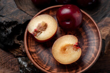 Fresh Sliced Red Plums On A Dark Wooden Background.