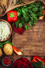 Wall Mural - Various uncooked vegetables, herbs and spices for healthy cooking and cutting board on rustic kitchen wooden table, top view. Preparation vegetarian cabbage, beetroot, tomato soup