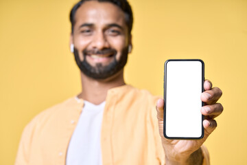 Happy indian man showing cellphone big mockup white blank phone template screen isolated on yellow background presenting smartphone mobile shop offer ads. Betting marketing, e learning webinars.