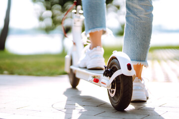 Legs of woman riding electric kick scooter on urban outdoor. Active life. Ecological transportation concept.