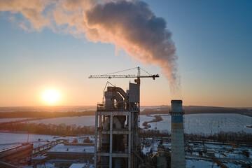 Poster - Aerial view of cement factory tower with high concrete plant structure at industrial production area at sunset. Manufacturing and global industry concept