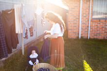 Sunlight Over Young Mother Getting Washing In With Baby In Bouncer