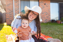 Happy Young Mum Wearing Hat Outside In Winter Sun Holding Happy Baby