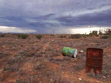 Old Barrels In Barren Landscape With Storm In Background