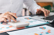 © Thapana_Studio - Top management is calculating profits and costs with calculators, analysis of growth and investment charts, business planning and strategies to maximize sales profits, long-term business plans.