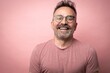Middle-aged guy with trendy eyeglasses. Mature beard attractive man in t-shirt isolated on pink background. Portrait of happy expressive smiling 50s old man with mustache and glasses