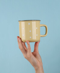 Wall Mural - Ceramic cup in female hand on blue background